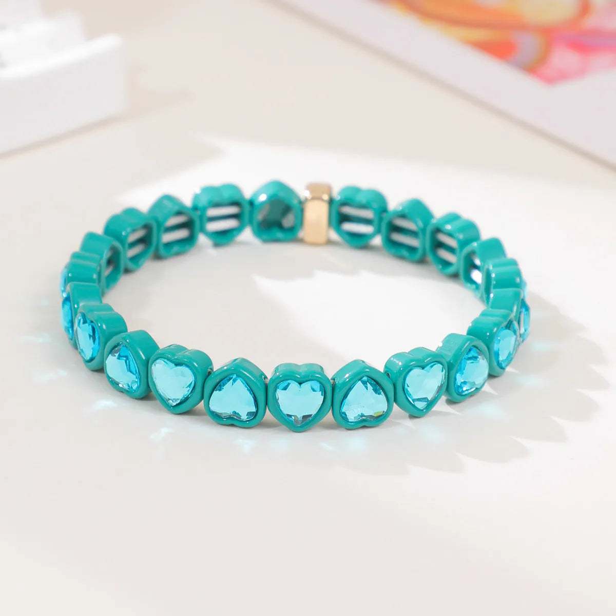 Colourful elastic bracelet with a shiny heart-shaped alloy charm on a stretch band.