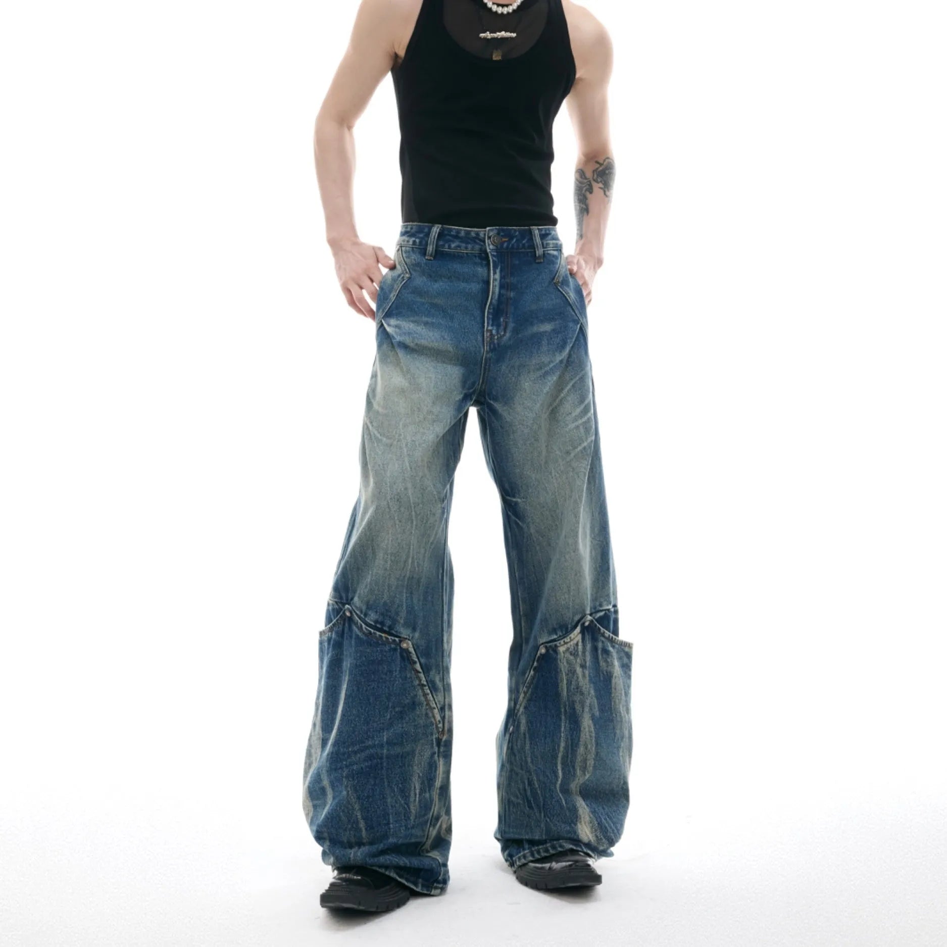 Man wearing verdant blue loose-fit jeans with curved seam detail and a vintage washed burst pattern.