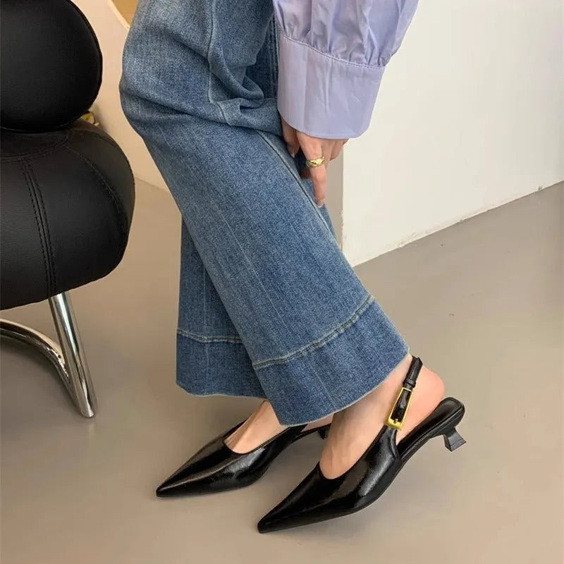 Black leather pointed toe women's shoes with a thin low heel and an ankle strap.