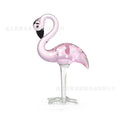 Pink flamingo decorative ornament made of white crystal on a table.