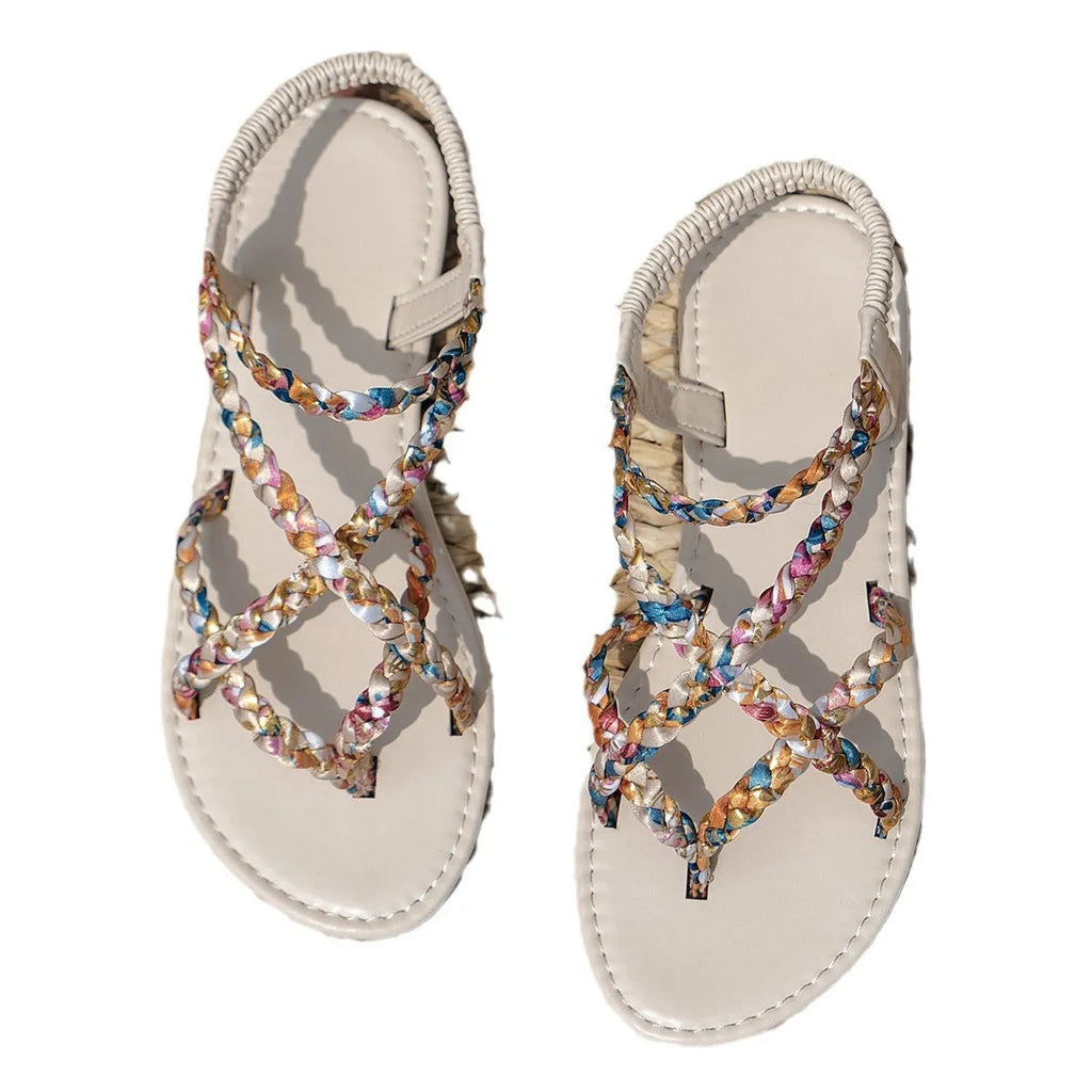 A pair of low-top flat sandals with a cloth upper and elastic band, shown in white.