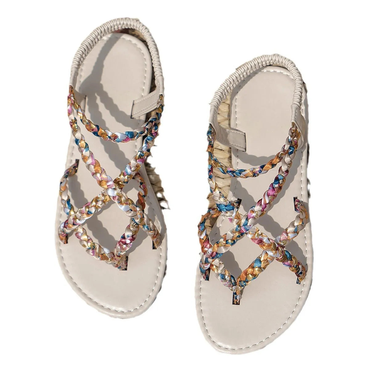 A pair of low-top flat sandals with a cloth upper and elastic band, shown in white.