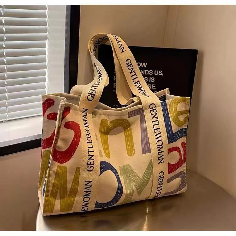 Large canvas women's tote bag with printed design, shown in shopping and travel use contexts.
