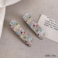 Two electroplated metal duckbill hairpins with hollow heart, star, and wave cut-out designs in silver tone