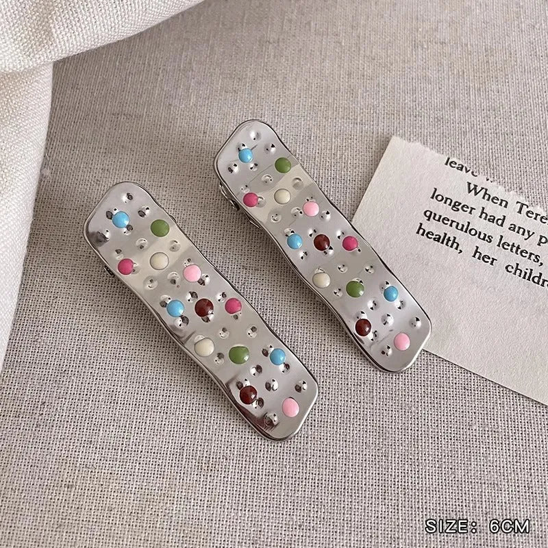 Two electroplated metal duckbill hairpins with hollow heart, star, and wave cut-out designs in silver tone