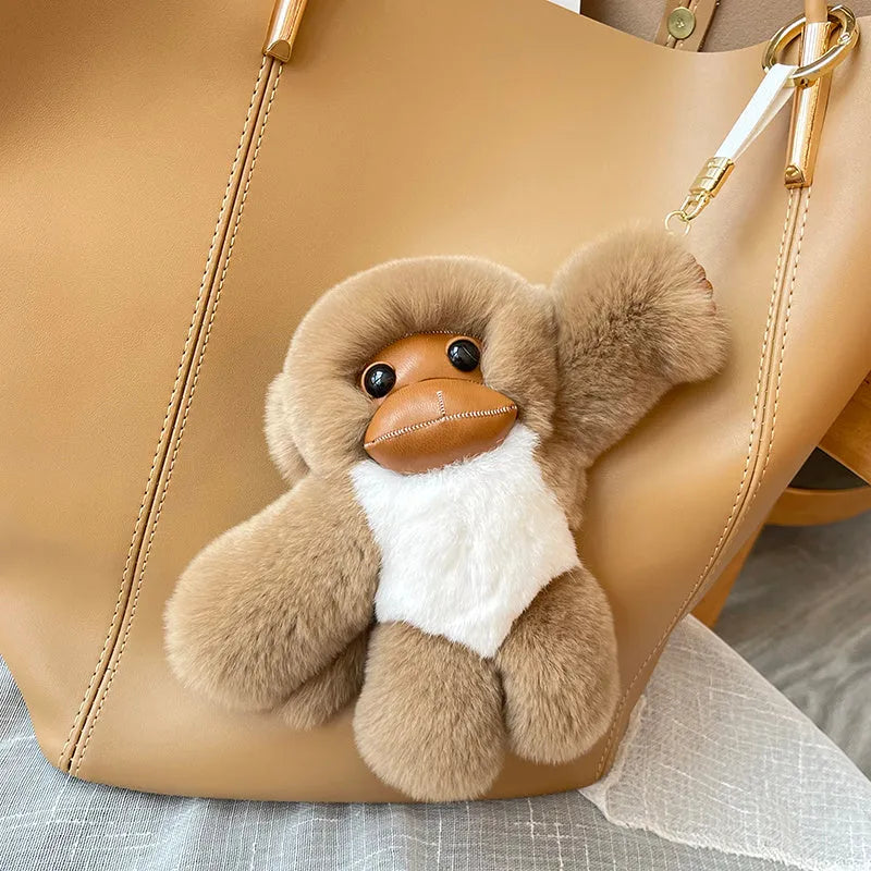 Lucky Little Monkey long arm Rex rabbit fur bag pendant in brown, attached to a bag strap