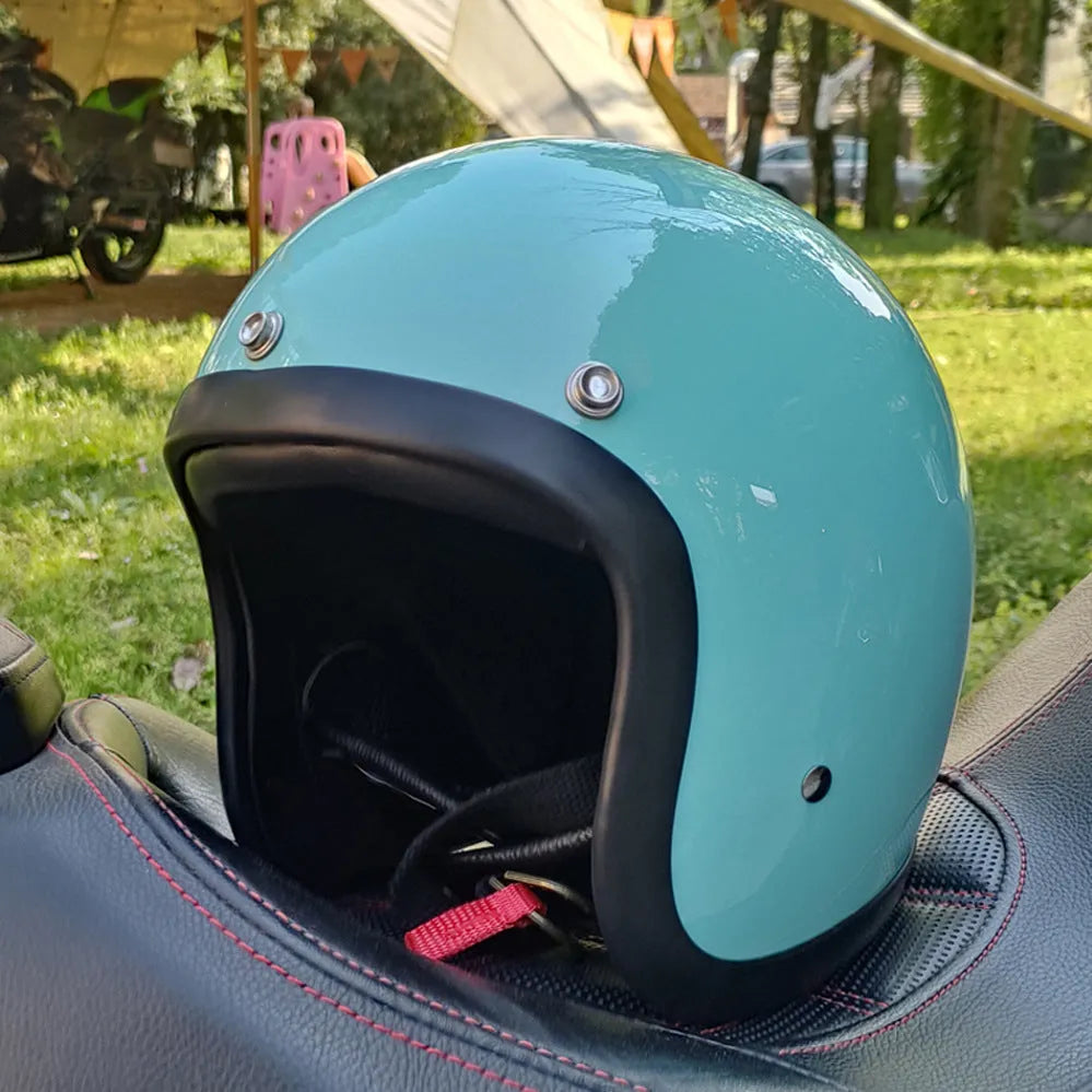 Retro-style half motorcycle helmet in fibreglass, shown in Cement Grey colour on a stand.