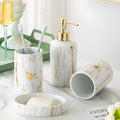 White ceramic bathroom wash kit set with two cups, a soap dish, and a bottle on a marble background.