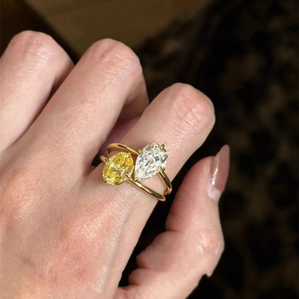 Geometric open-back silver ring with large central pear-cut clear zircon stone on a model's hand.