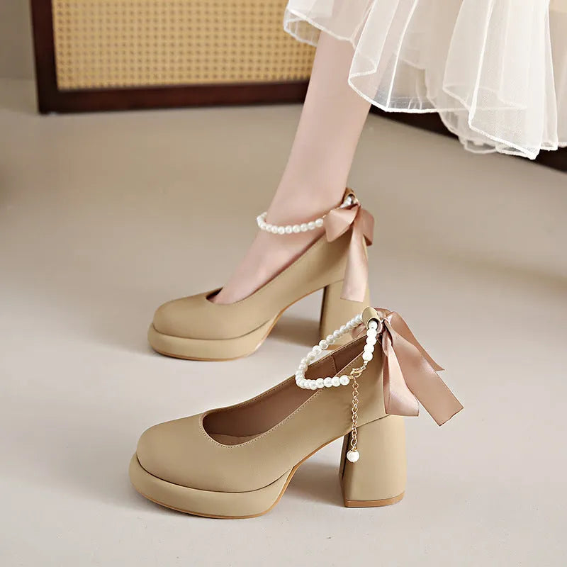Beige women's Mary Jane shoes with chunky heel, round toe, and pearl- detail ankle strap on a white background.