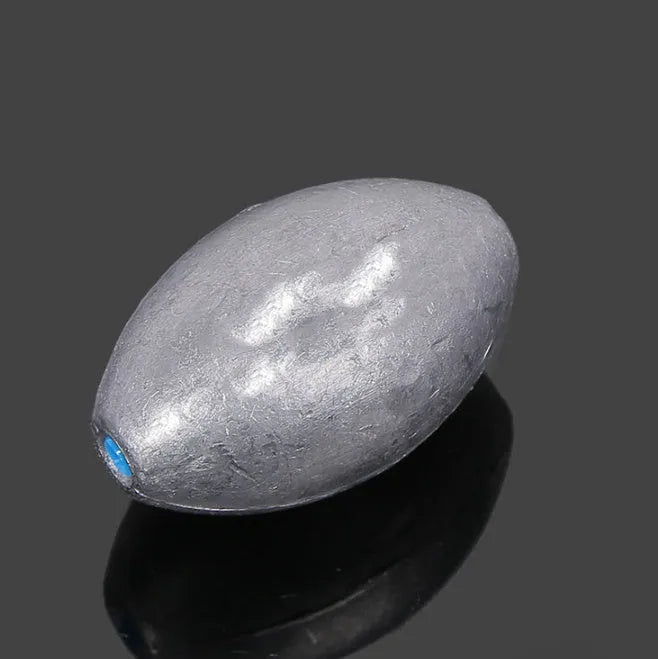 Close-up of a grey olive-shaped lead fishing sinker with scale texture, showing the central hole for rigging.
