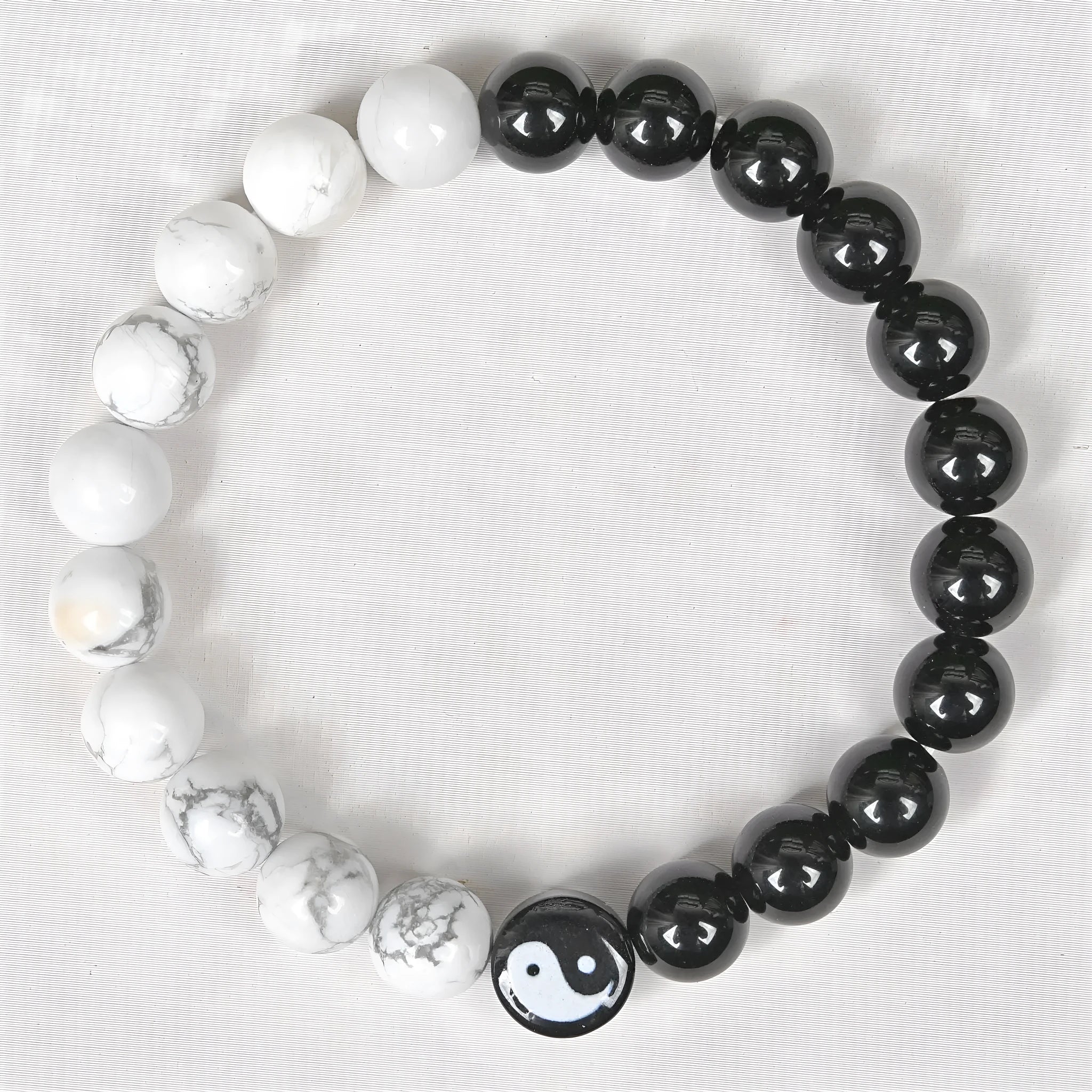 Natural obsidian and white turquoise 8mm bead bracelet on a neutral background