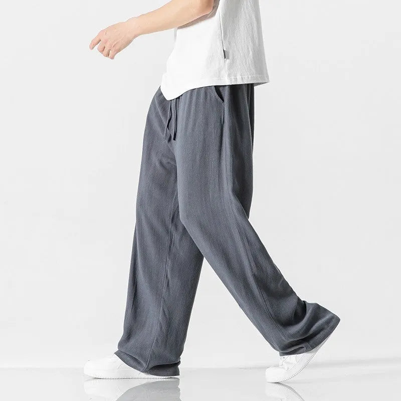 Man wearing beige bamboo fibre cropped trousers with a drawstring waist and straight legs.