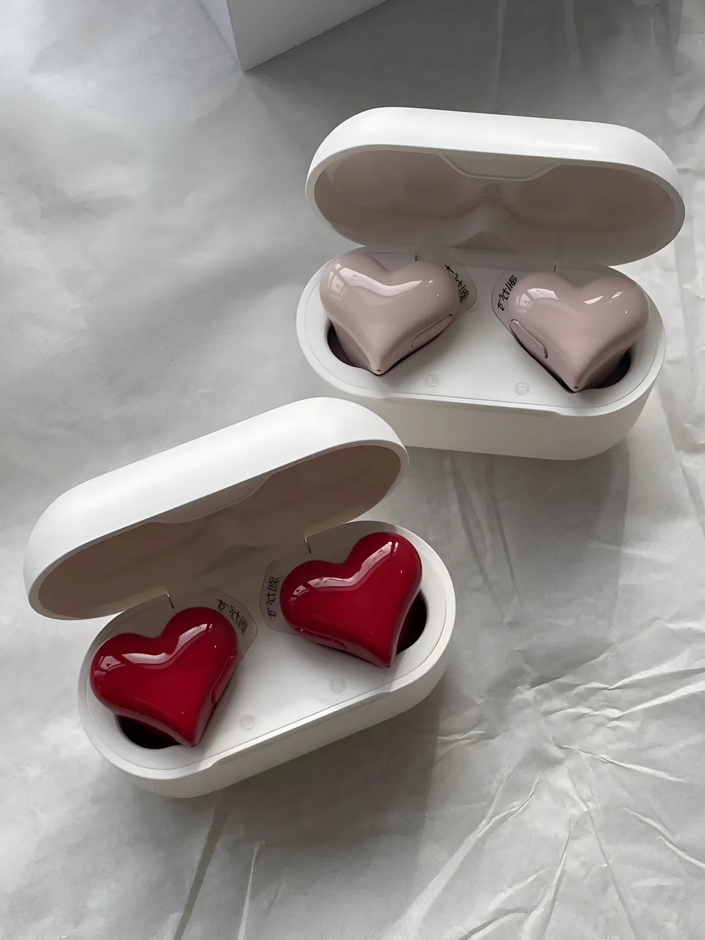 Heart-shaped wireless Bluetooth earphones in Chinese red and girl pink colours with charging cable