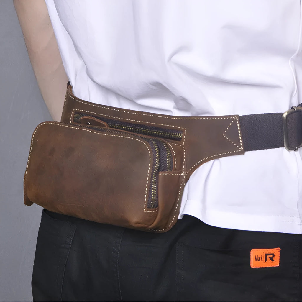 Brown top layer cowhide men's waist bag with pull cord closure, shown with a 10-inch laptop and mobile phone.