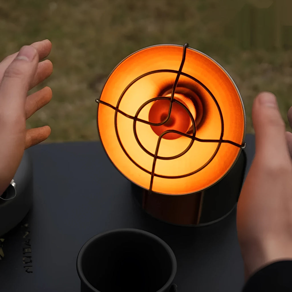 Black and orange mini portable outdoor gas heater stove with automatic ignition on a surface.