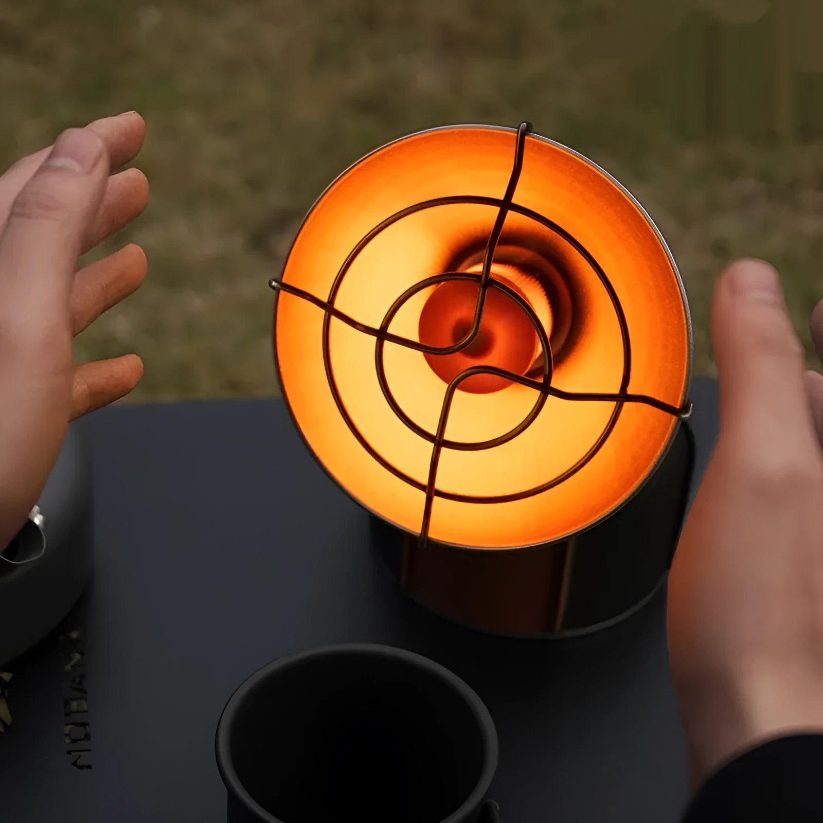 Black and orange mini portable outdoor gas heater stove with automatic ignition on a surface.