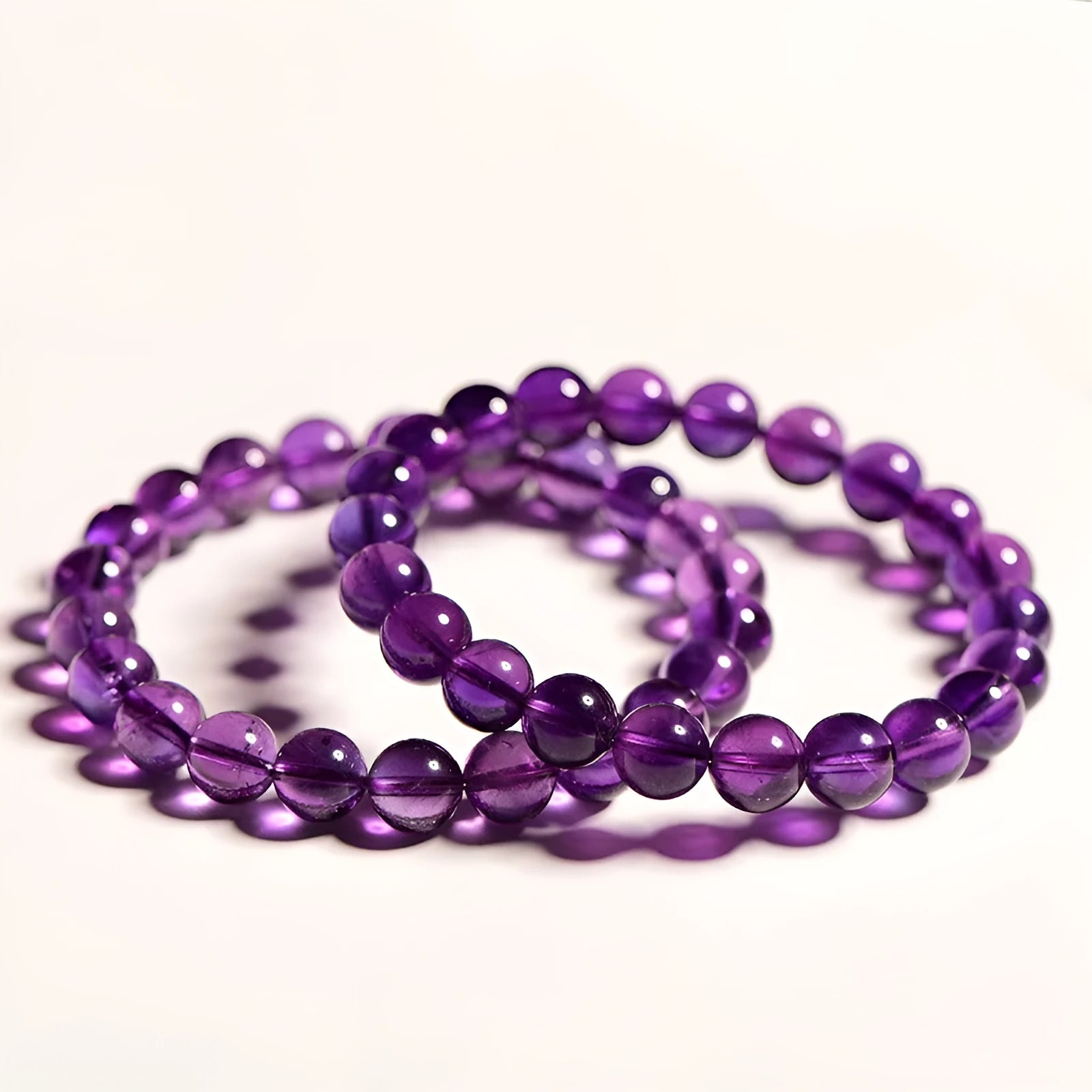 Loose polished amethyst beads on an elastic cord, forming a natural Uruguay crystal bracelet in violet shades.