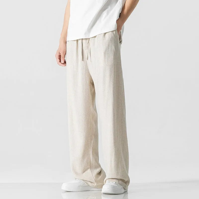 Man wearing beige bamboo fibre cropped trousers with a drawstring waist and straight legs.