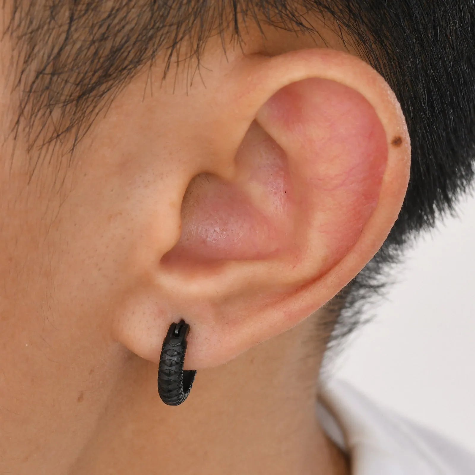 A pair of men's stainless steel earrings featuring a black snake pattern design, shown front-on.