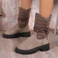 Black women's high-top snow boots with a chunky heel and lace-up front on a grey background.