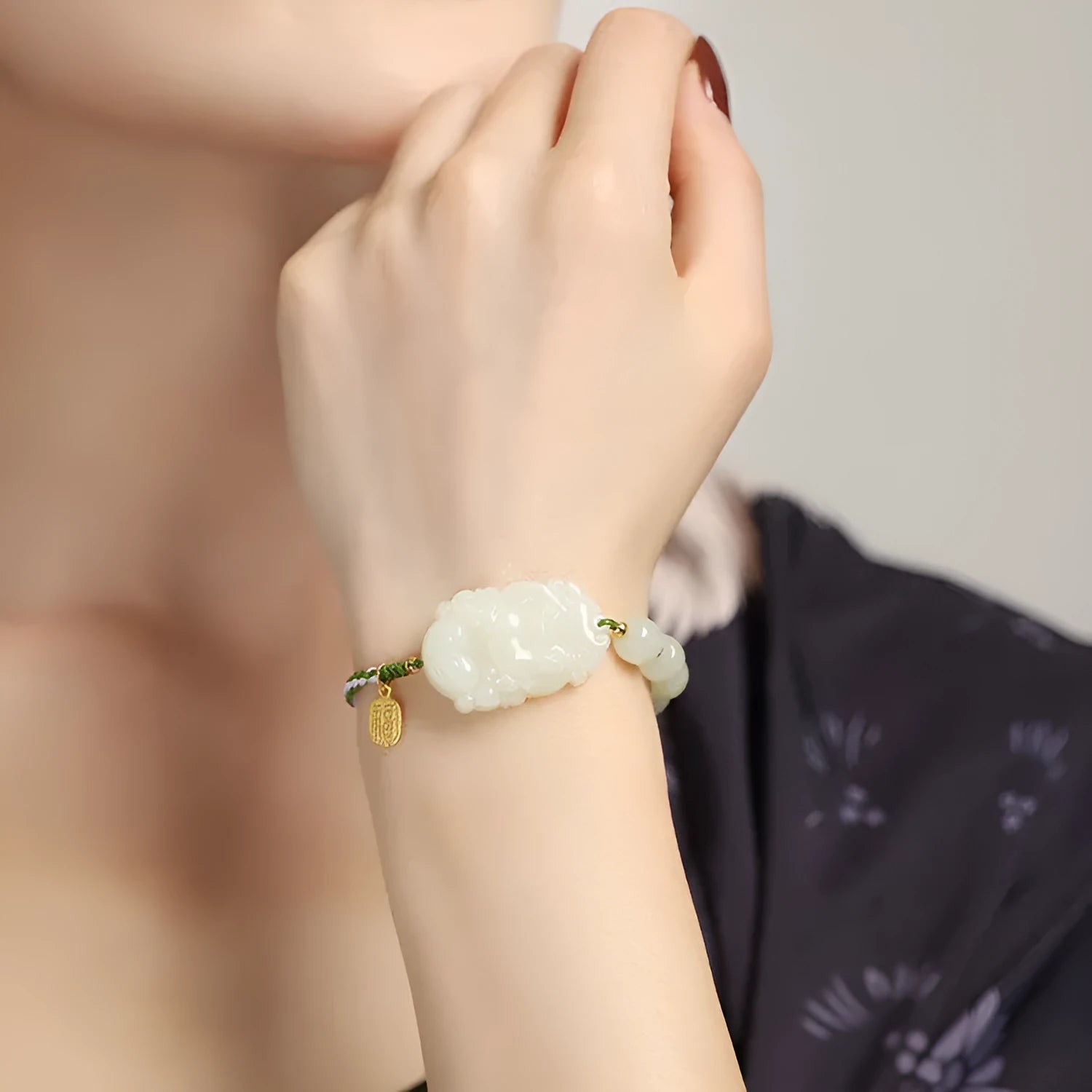 Hetian Jade Zodiac Bracelet on wrist showing rabbit charm, silver card, and red ice cotton rope.