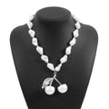 Gold tone irregular necklace with cherry fruit pendant and adjustable string of round pearls on a model