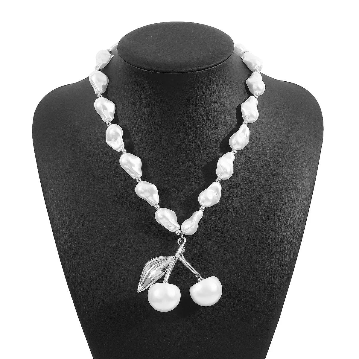 Gold tone irregular necklace with cherry fruit pendant and adjustable string of round pearls on a model