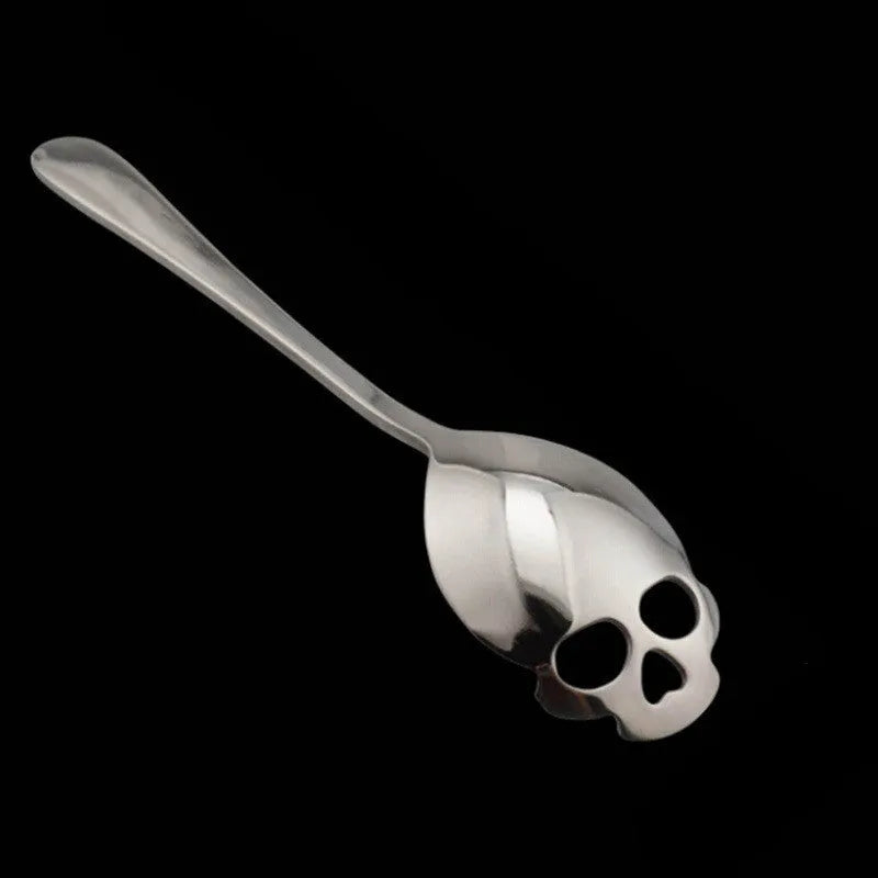 Stainless steel skull-shaped coffee spoon with polished finish on a flat surface