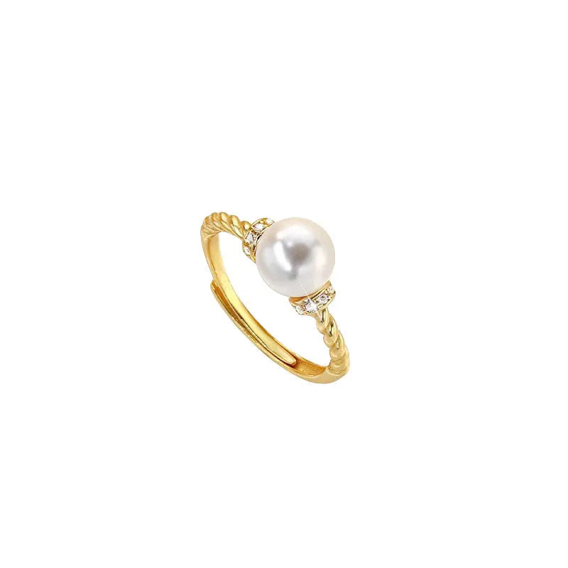Antique finish copper ring with geometric twist and central inlaid pearl on a wooden background