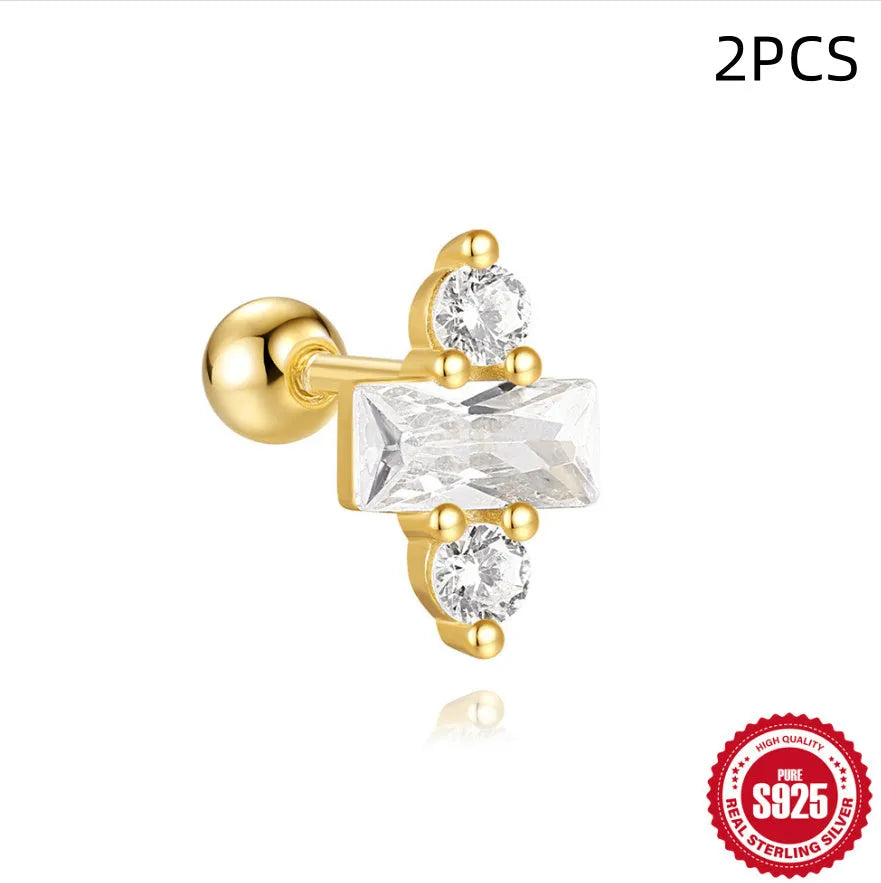 Close-up of women's flower-shaped sterling silver stud earrings with red square gravel stones and a gold electroplated finish.