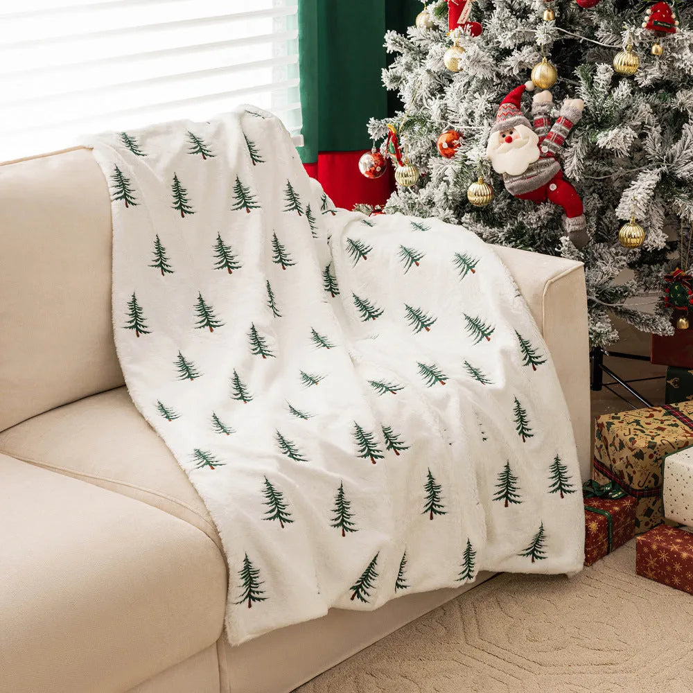 White plush sofa blanket with embroidered Christmas tree design on a sofa