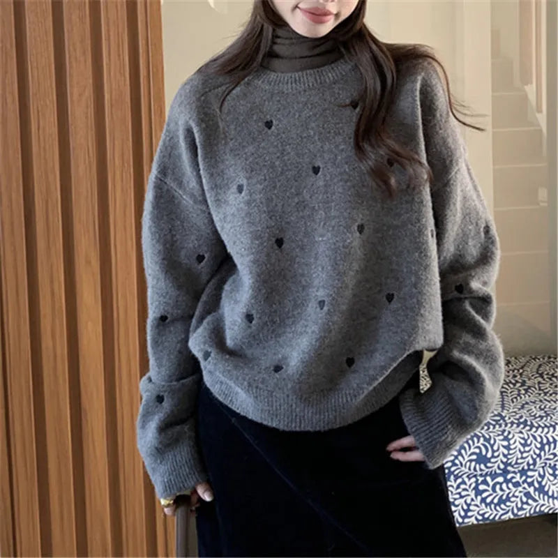 Women's loose grey acrylic pullover sweater with embroidery on the chest and long sleeves.