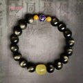 Golden obsidian bracelet with geometric beads and a detailed zodiac animal charm on a wrist.