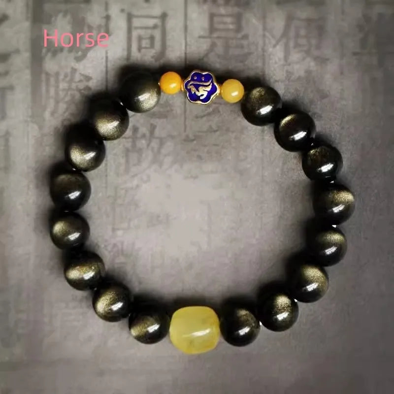 Golden obsidian bracelet with geometric beads and a detailed zodiac animal charm on a wrist.