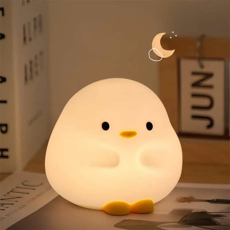 Cute duck-shaped silicone LED night lamp with touch sensor and warm glow on a bedside table