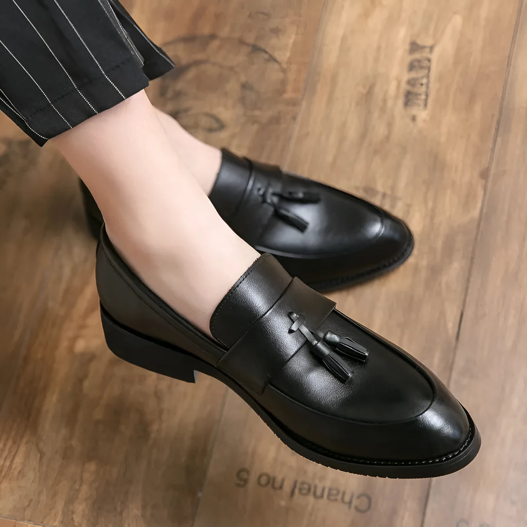 Men's black slip-on loafers with a tassel decoration on a pointed-toe, low-top artificial PU upper.