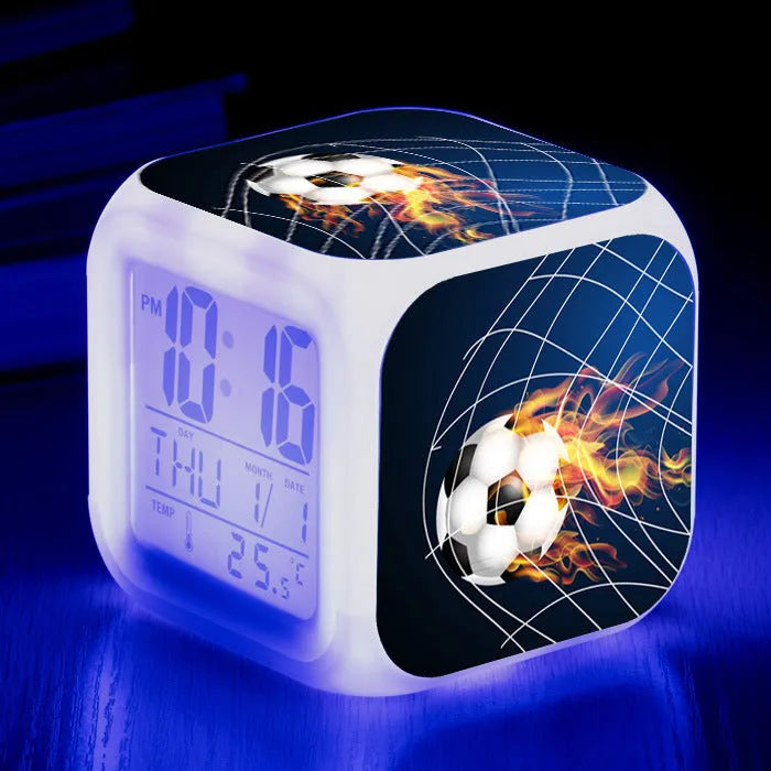 Square cartoon football pattern children's alarm clock with mute alarm on a bedside table.