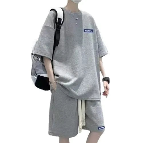 Man wearing a grey waffle-textured short-sleeved top and matching shorts from a casual leisure suit.