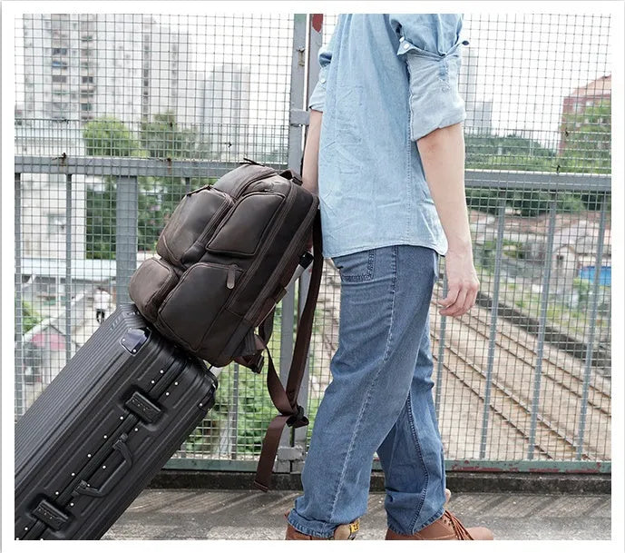 Dark brown men's leather backpack open to show internal compartments for a 17-inch laptop and organisation pockets.