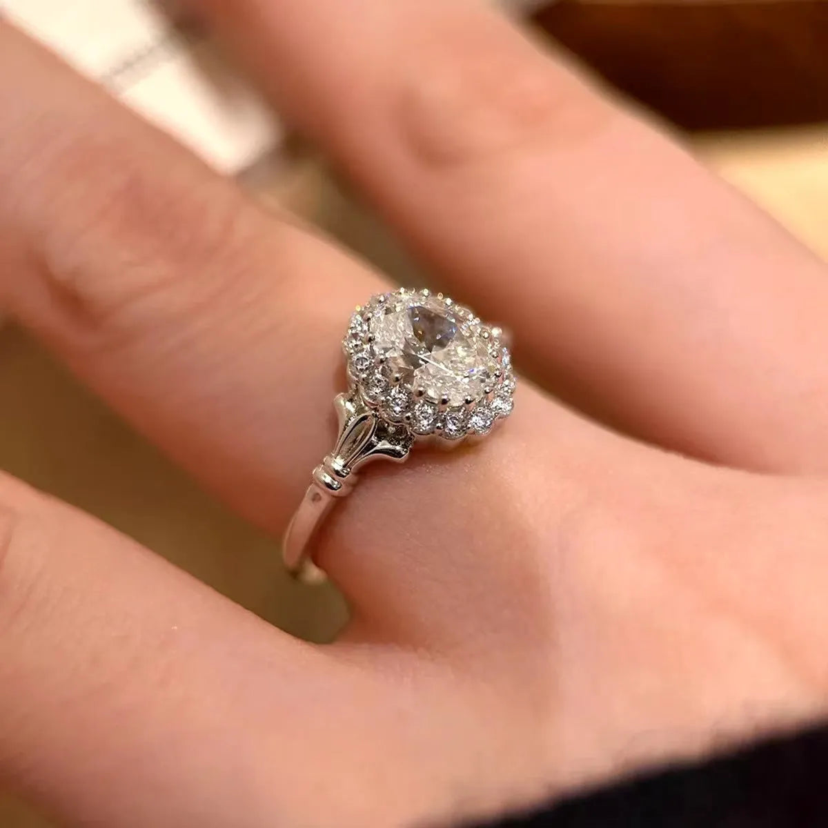 Close-up of a silver women's ring with an adjustable geometric band and a large oval bridal bouquet style diamond cluster.