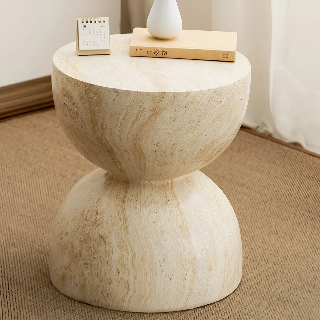 Modern hourglass-shaped tea table in imitation cave stone finish placed beside a sofa in a living room