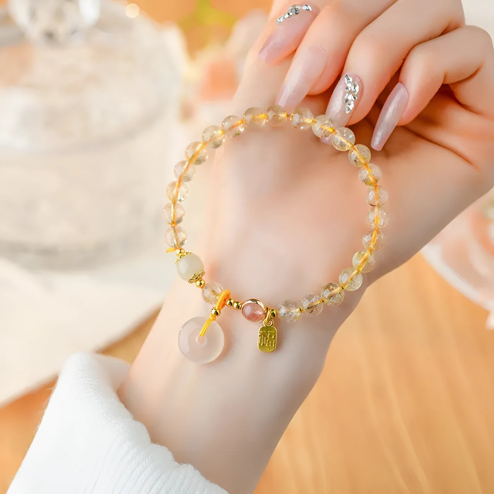Gold rutilated quartz bracelet with a peace buckle pendant and geometric safety clasp.
