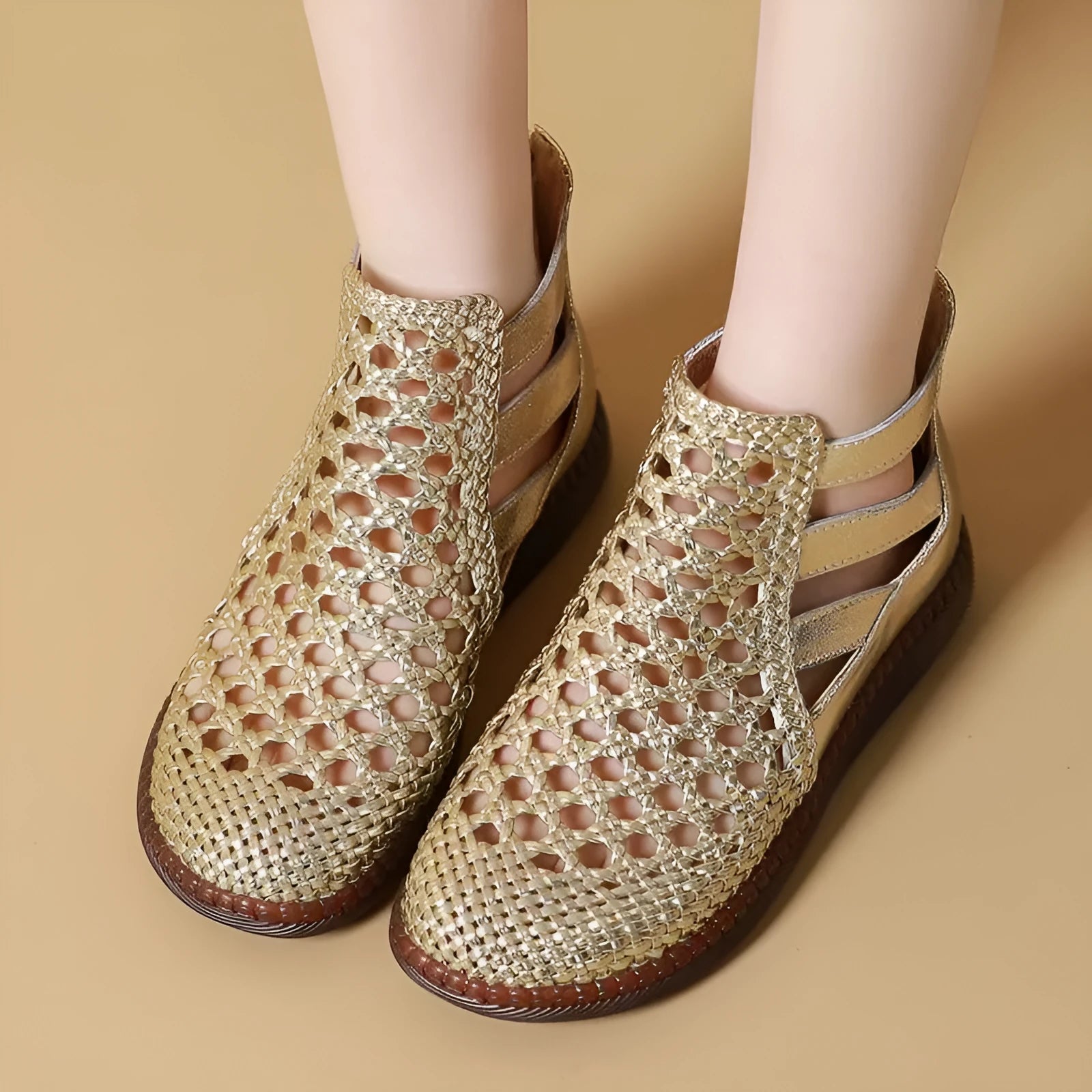 Gold flat sandals with round toe and breathable hollow-out design on a white background.