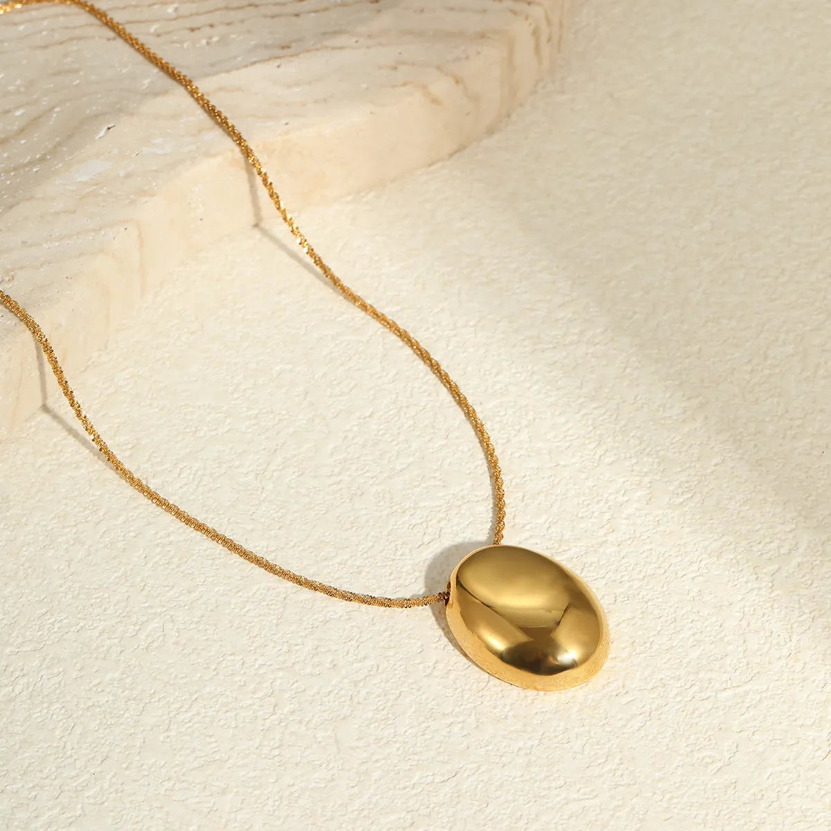 Gold geometric pendant necklace on a stainless steel chain with adjustable length.