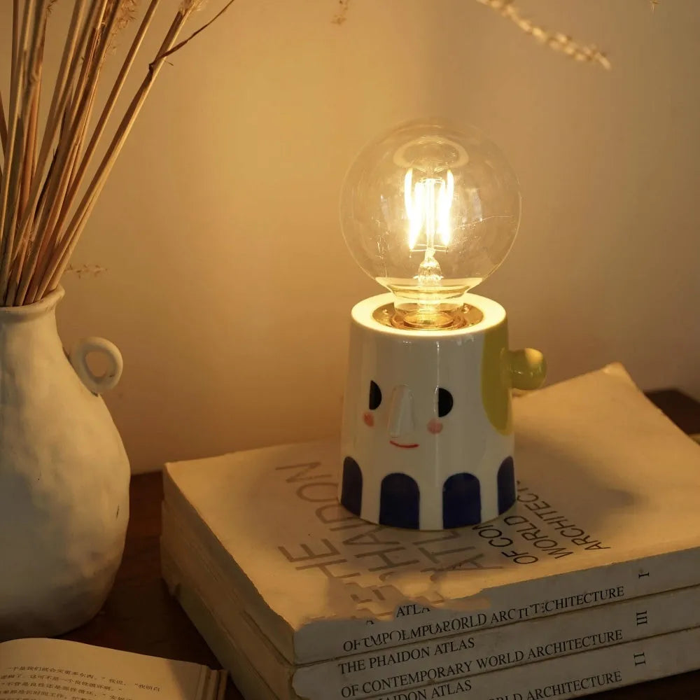 Handmade solid ceramic table lamp with spherical white shade on a wooden surface, showing UK plug.