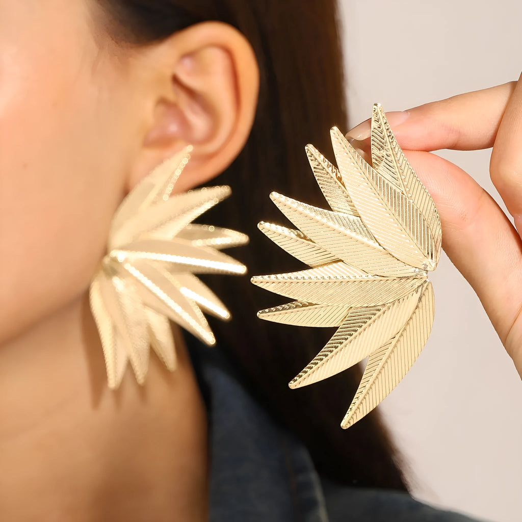 Gold and white alloy leaf-shaped patch earrings on a plain background