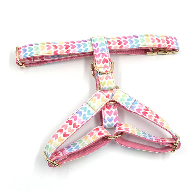 Pink dog harness with gold buckle and heart-shaped stone decoration on white background