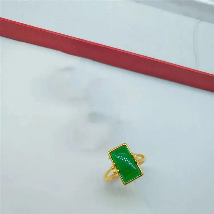 Close-up of an adjustable brass gold-plated ring with an electroplated finish and a green artificial gemstone inlay.