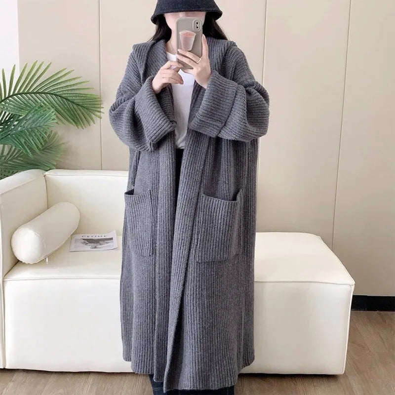 Woman wearing a longline loose grey hooded cardigan coat with raglan sleeves.